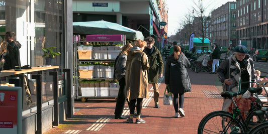 a group of people walking down a street next to tall buildings